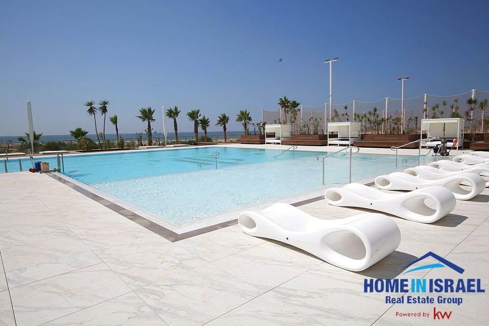 Briga Towers luxury pool with lounge chairs and palm trees in Netanya