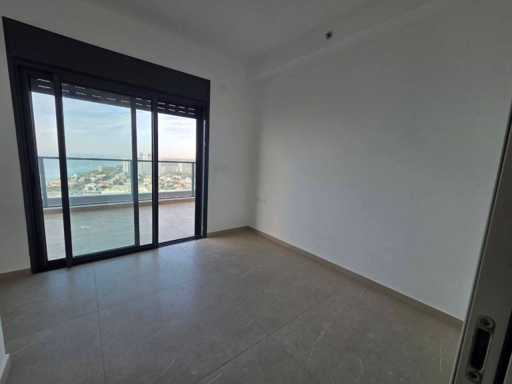 Luxury master bedroom with sea view windows and modern en-suite bathroom in Netanya rental.